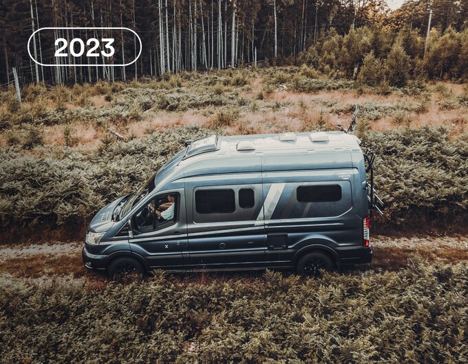 Carado motorhome camper van in side view on a country lane, surrounded by low scrub and woodland