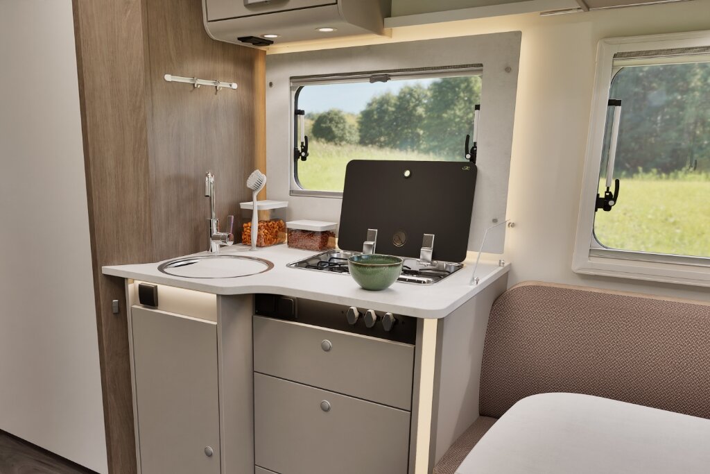 Küche im Carado Wohnmobil mit Spüle, Gasherd und Sitzbank am Fenster