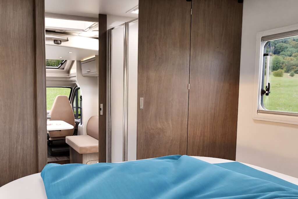 Sleep space in the Carado motorhome with bed, wardrobe and a view to the lounge area