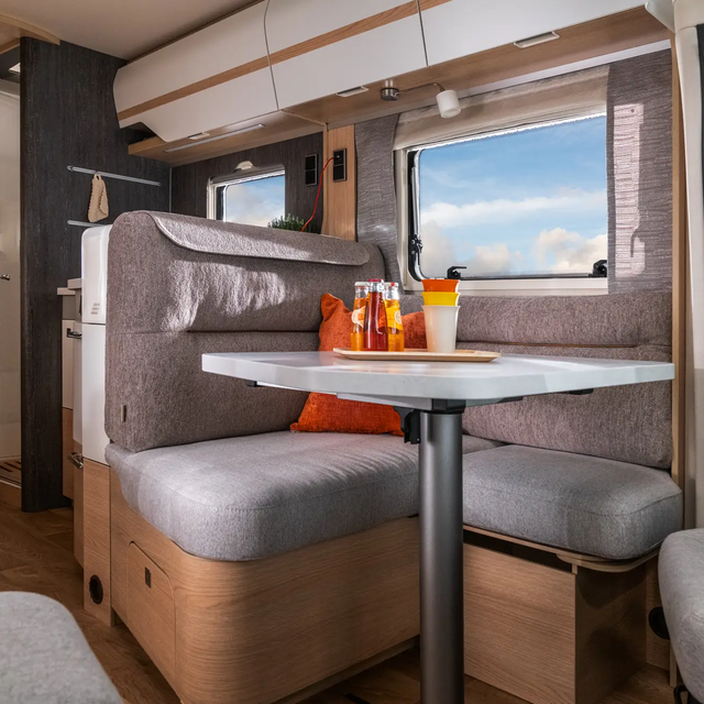 Utsikt fra dekket sittegruppe og kjøkkenblokk gjennom vinduene i HYMER B ML-T 780 til solfylt blå himmel