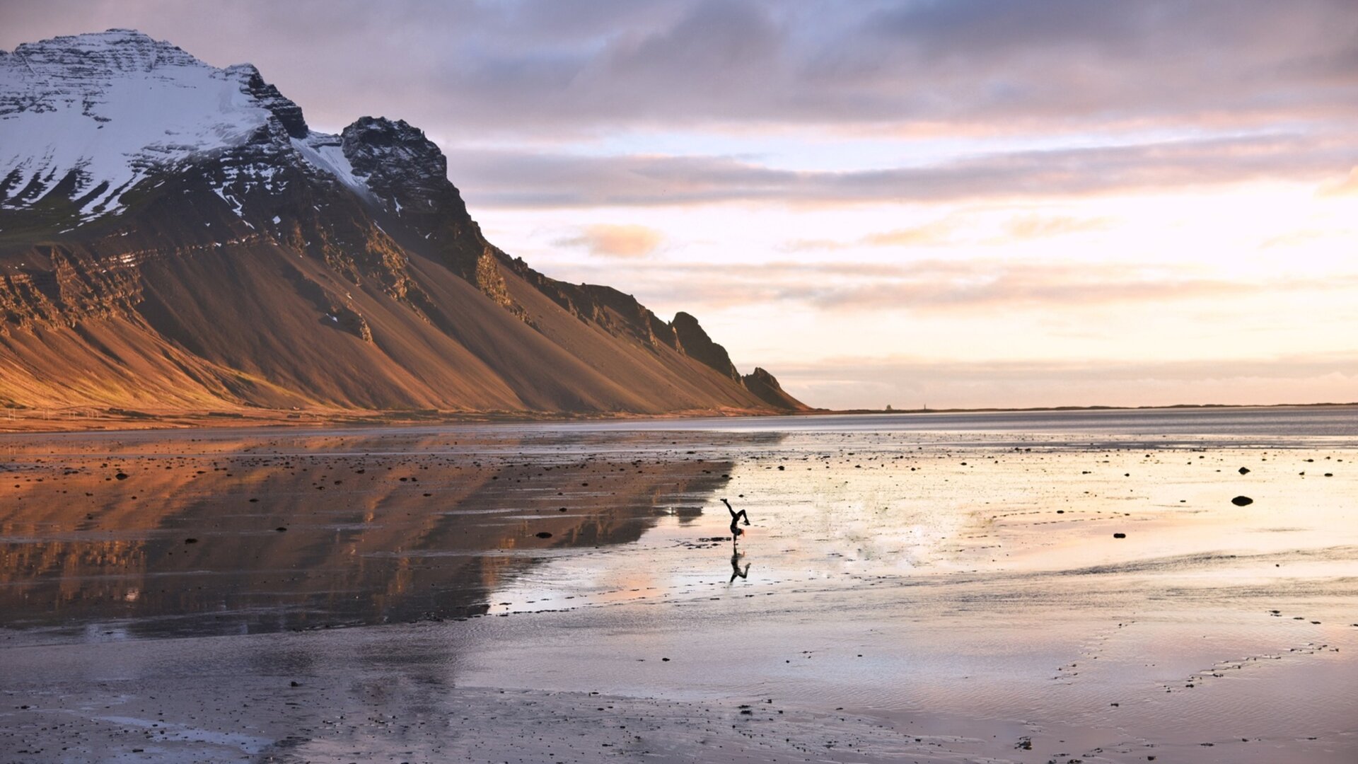 Een landschap weerspiegelt de lucht op een nat oppervlak, besneeuwde bergen zijn te zien. Uit het reisverslag "Met de camper naar IJsland".